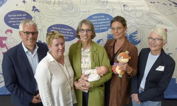 Fünf Personen stehen vor einem Poster