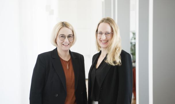 Zwei Personen stehen nebeneinander und schauen in die Kamera.