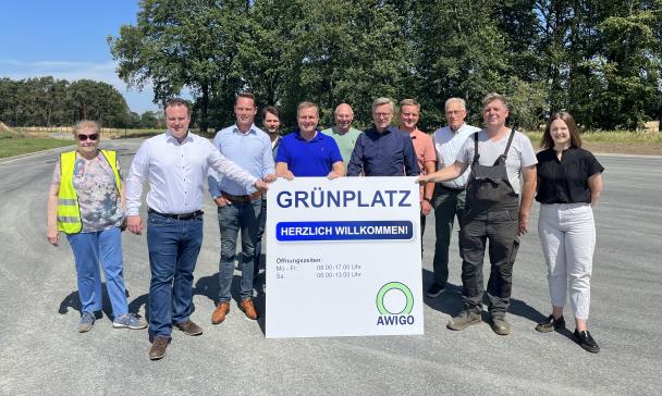 Eine Personengruppe steht auf einem großen Platz und hält ein Schild in den Händen.