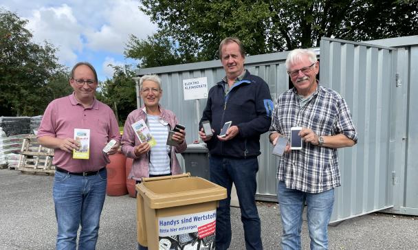 Vier Personen stehen hinter einer Abfalltonne