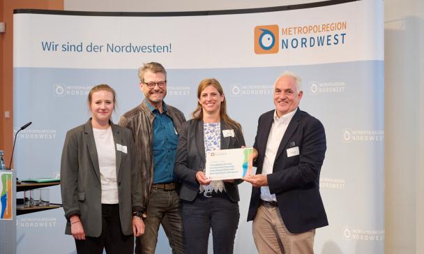 Vier Personen stehen vor einem großen Poster