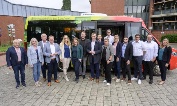 Eine Personengruppe steht vor einem Kleinbus.