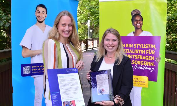 Zwei Personen stehen vor zwei Werbe-Plakaten