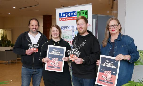 Vier Personen stehen in einem Foyer.