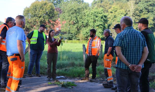 Eine Personengruppe steht am Rand einer Wiese.