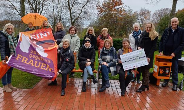 Eine Personengruppe an einer orangefarbenen Sitzbank.