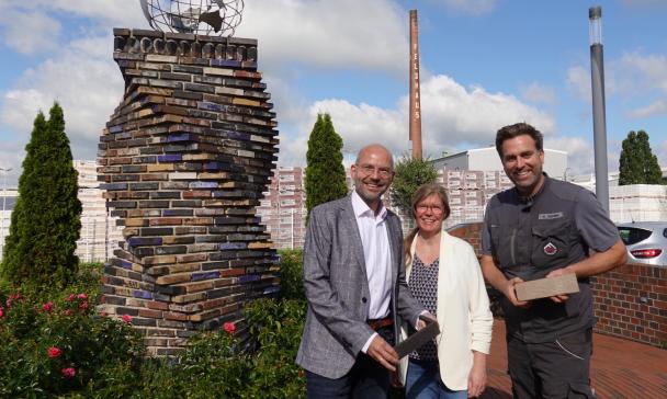 3 Personen im Freien vor Skulptur