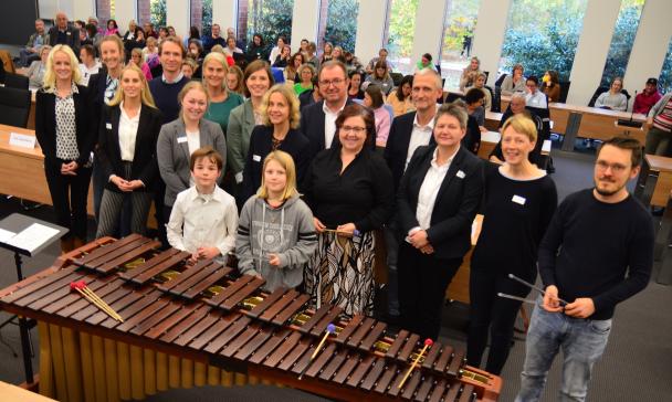 Eine Personengruppe steht in einem Koferenzsaal.
