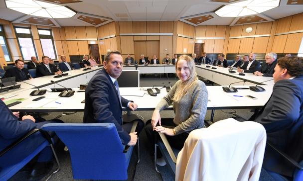 Eine Personengruppe sitzt in einem Sitzungssaal.