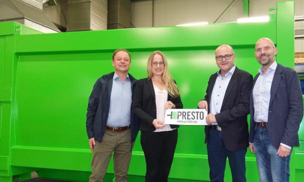 Vier Personen stehen vor einer Industrieanlage