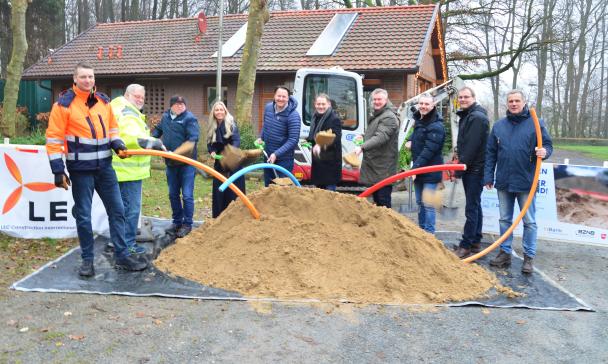 Eine Gruppe von Personen steht vor einem ausgegrabenen Erdhaufen