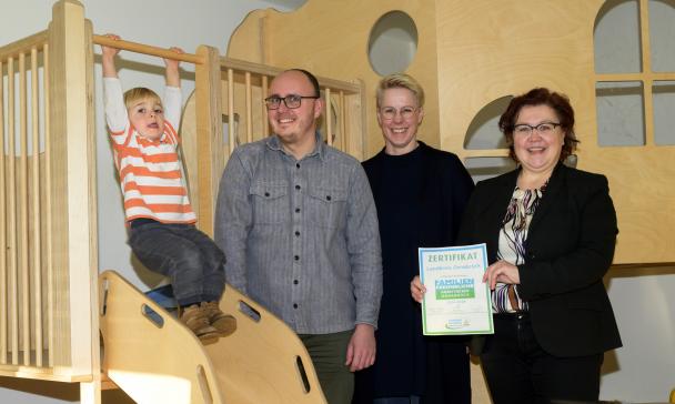 Vier Personen stehen in einem Raum mit Klettergerüst.