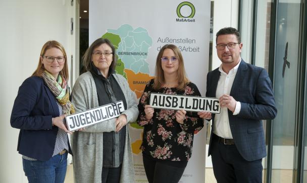 Vier Personen stehen vor einem Roll Up Poster.