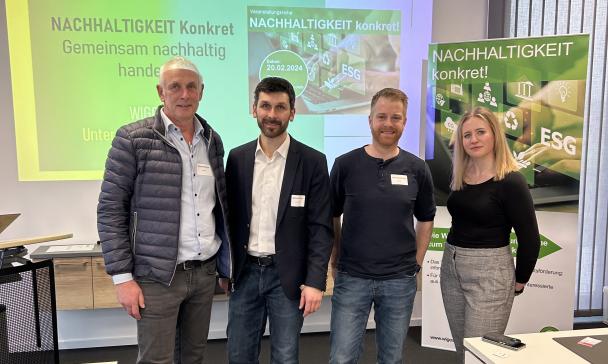 Vier Personen stehen vor einer Videopräsentationswand.