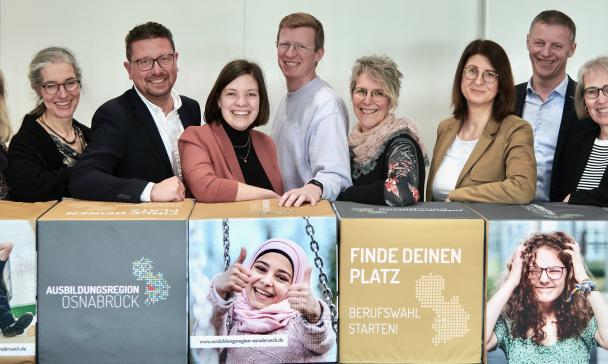 Gruppe von Personen vor einem Tresen mit Plakaten