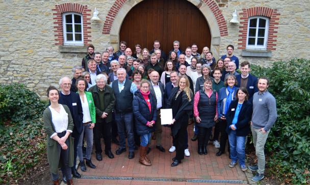 Eine Personengruppe steht vor dem Eingang eines historischen Gebäudes.