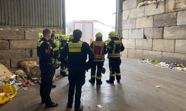 Eine Personengruppe in Uniformen steht in einer Lagerhalle.