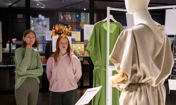 Zwei Personen betrachten ein Figur in einer Ausstellung.