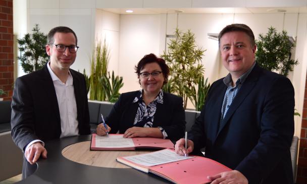 3 Personen vor Tisch stehend
