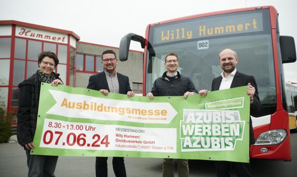 Vier Personen mit einem Banner in den Händen stehen vor einem Linienbus.
