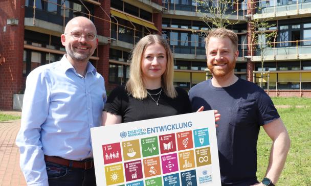 3 Personen mit Plakat im Freien