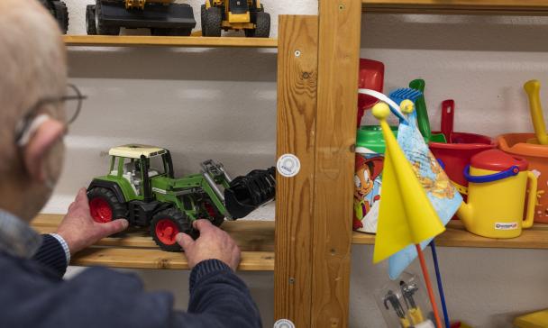 Eine Person steht vor einem Regal mit Spielzeug.