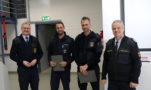 Vier Personen in Uniform stehen in einer Halle.