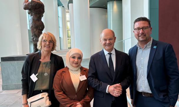 Vier Personen stehen im Foyer eines Gebäudes.
