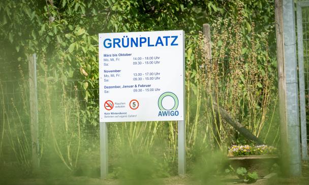 Schild an einem Zaun mit Grünzeug dahinter