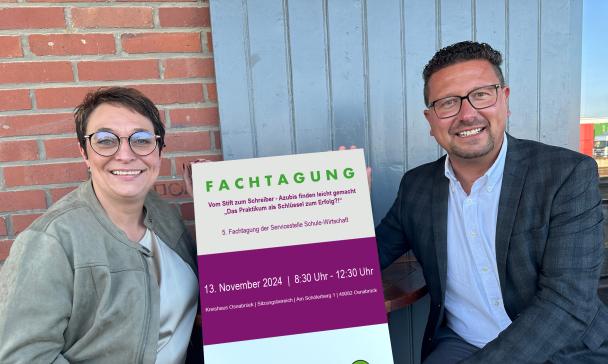 Zwei Personen halten ein Schild in die Kamera.