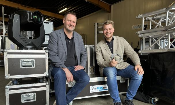 Zwei Personen sitzen auf Bühnentechnik-Elementen.