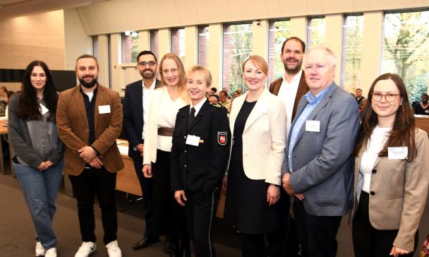 Eine Personengruppe steht in einem Veranstaltungssaal..