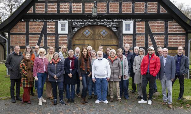 Eine Personengruppe steht vor der Giebelseite eines Fachwerkhauses.