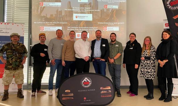 Eine Personengruppe steht vor einer Projektionsfläche.