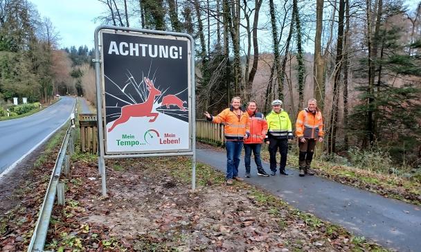Vier Personen stehen neben einem Warnschild Wildwechsel