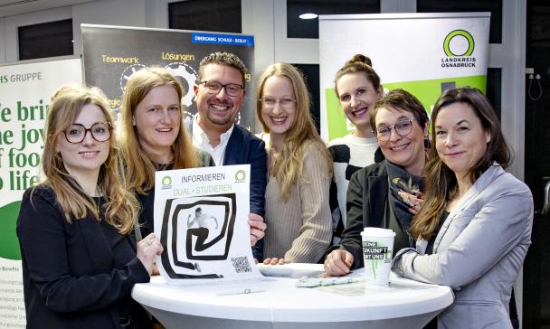 Gruppe von Personen um einen Tisch stehend