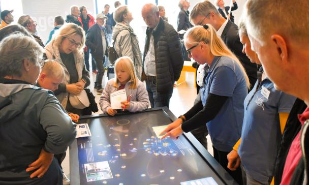 Eine Personengruppe steht um einen Display-Tisch herum.