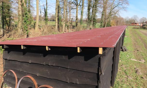 Ein Schuppen steht vor einer Baumreihe.