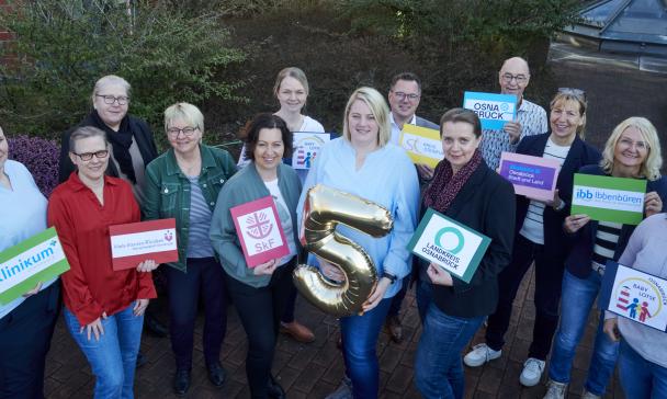 Eine Personengruppe schaut nach oben in die Kamera.