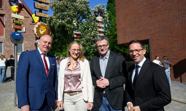 Vier Personen stehen vor einem Backsteingebäude.