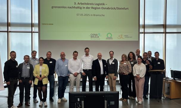 Eine Personengruppe seht in einem Veranstaltungssaal.