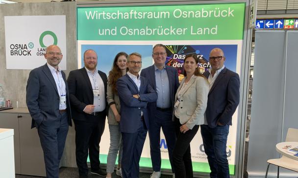 Eine Personengruppe steht auf einem Messestand.