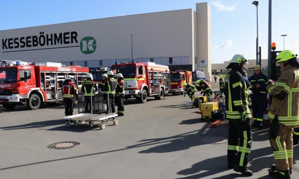 Feuerwehrfahrzeuge stehen vor einer Werkhalle.