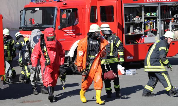 Personen in Schutzkleidung vor einem Feuerwehrfahrzeug