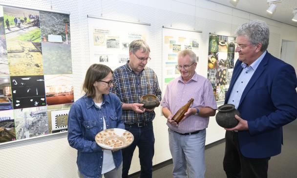 Vier Personen stehen vor einer Wand mit Postern.