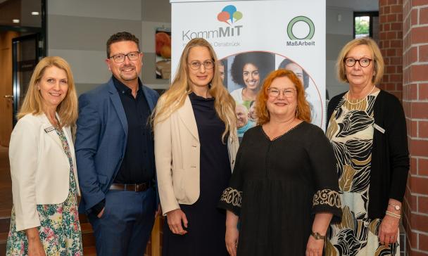 5 Personen vor Plakat