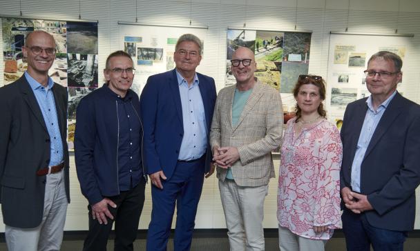 Sechs Personen stehen vor einer Wand mit Postern.