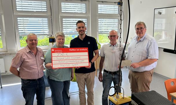 Fünf Personen präsentieren ein symbolischen Spendenscheck