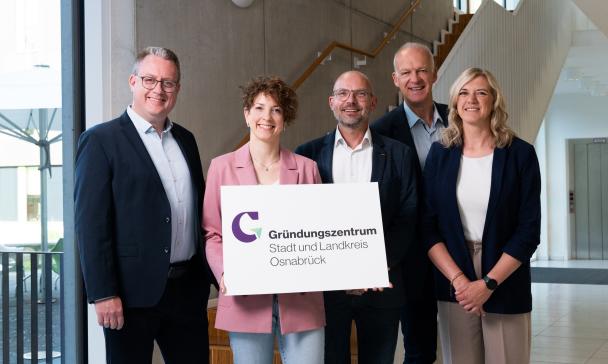 Fünf Personen stehen im Treppenhaus eines Bürogebäudes.