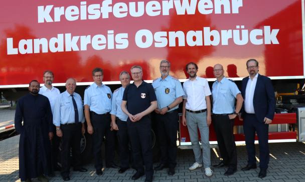 Eine Personengruppe steht vor einem Feuerwehrfahrzeug